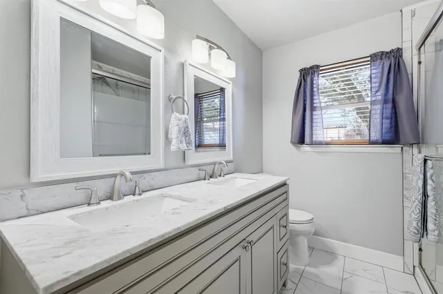a bathroom with a granite countertop sink a toilet and a mirror