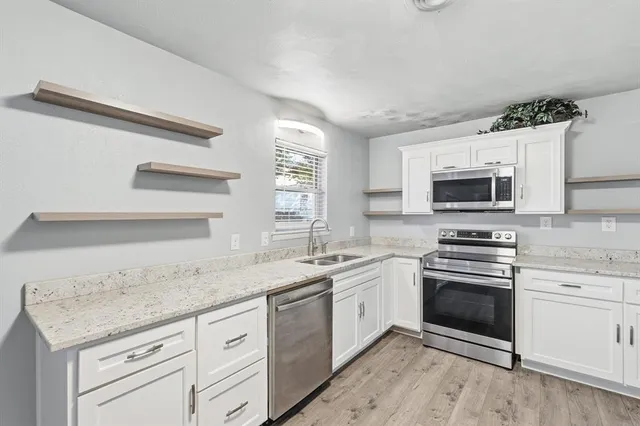 a kitchen with granite countertop stainless steel appliances a stove sink and microwave
