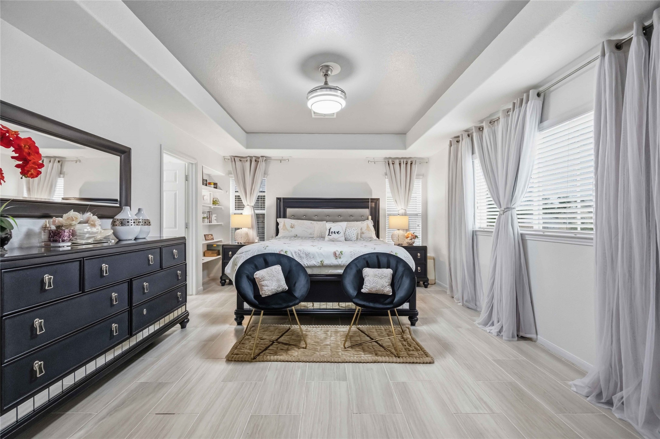 2139 Pacific Loon Lane Conroe, TX 77385 - Photo 16 of 21 Elegant primary retreat with soaring tray ceilings, expansive windows, and designer finishes throughout. Spacious layout offers a serene atmosphere with plenty of natural light and room for a private sitting area.