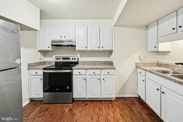 a kitchen with stainless steel appliances granite countertop a stove a sink and white cabinets