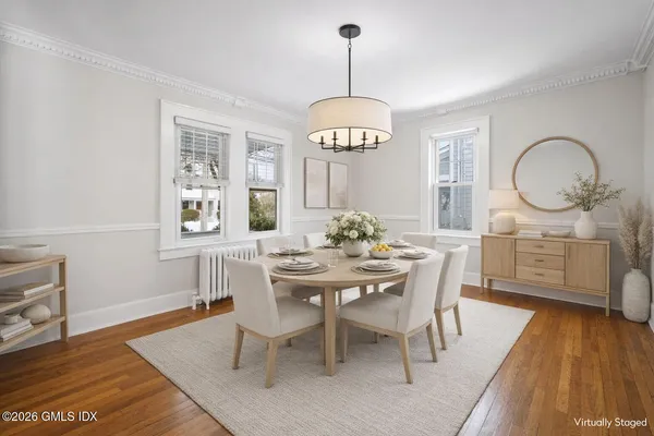 a dining room with wooden floor a chandelier a wooden table and chairs