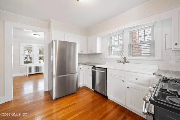 a kitchen with a refrigerator stove and wooden floor