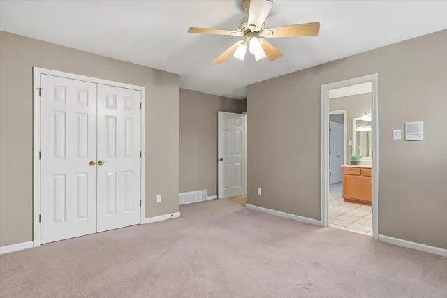 an empty room with closet and a ceiling fan