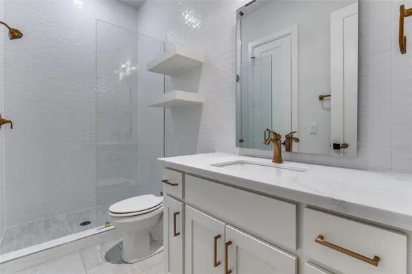 a bathroom with a granite countertop sink a toilet and a shower