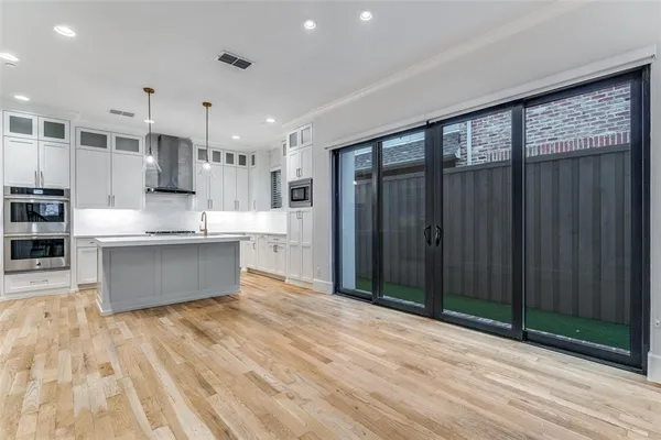 a large kitchen with stainless steel appliances granite countertop a large counter top a stove and a wooden floors