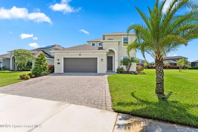 a front view of a house with garden and trees