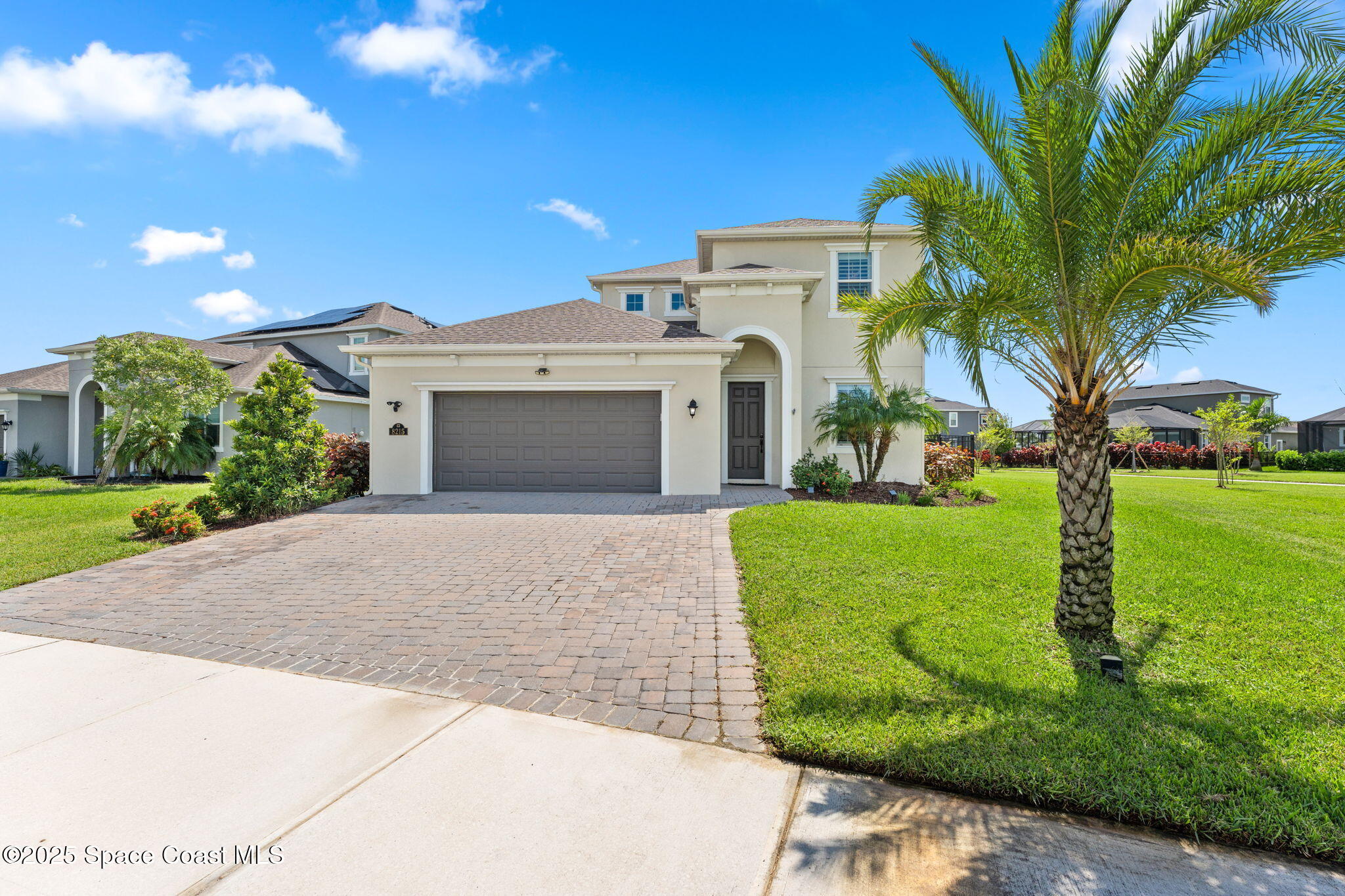 a front view of a house with garden and trees