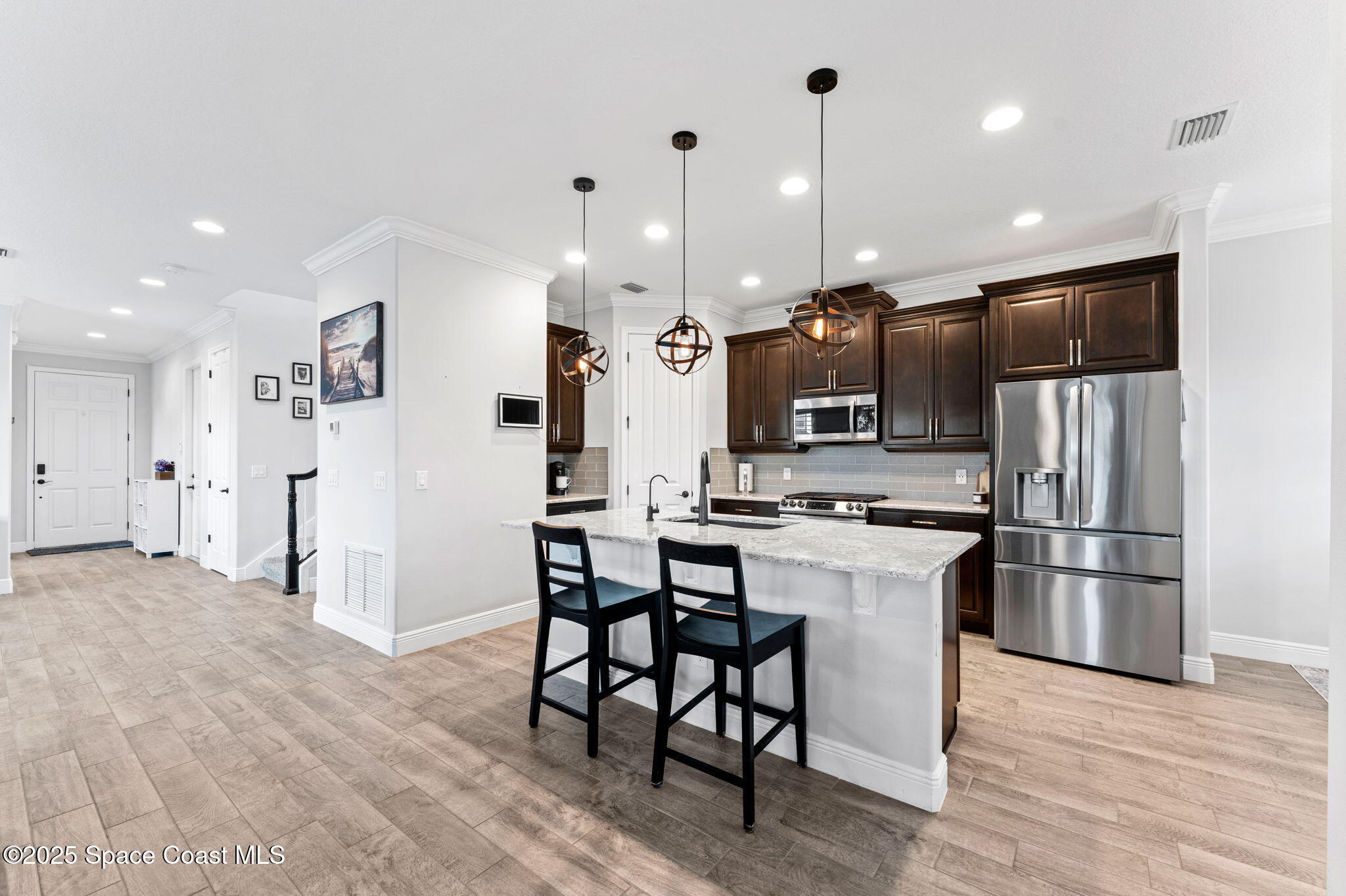 8215 Millbrook Avenue Melbourne, FL 32940 - Photo 15 of 62 a kitchen with stainless steel appliances kitchen island granite countertop a refrigerator a stove a oven a sink with a dining table and chairs