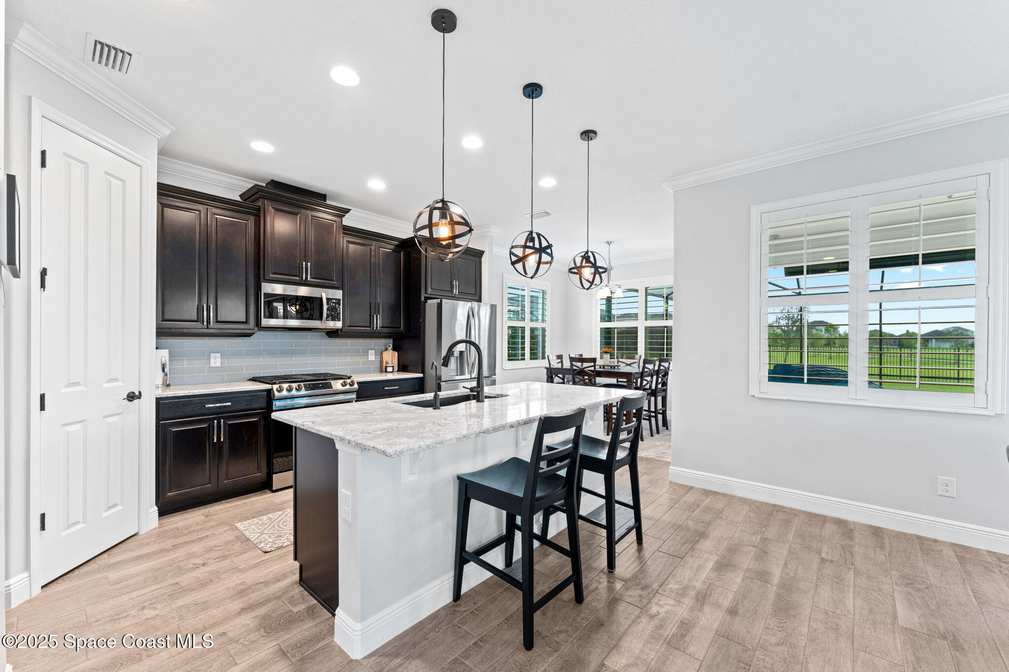 8215 Millbrook Avenue Melbourne, FL 32940 - Photo 16 of 62 a kitchen with stainless steel appliances kitchen island granite countertop a stove a refrigerator a oven a sink with a dining table and chairs