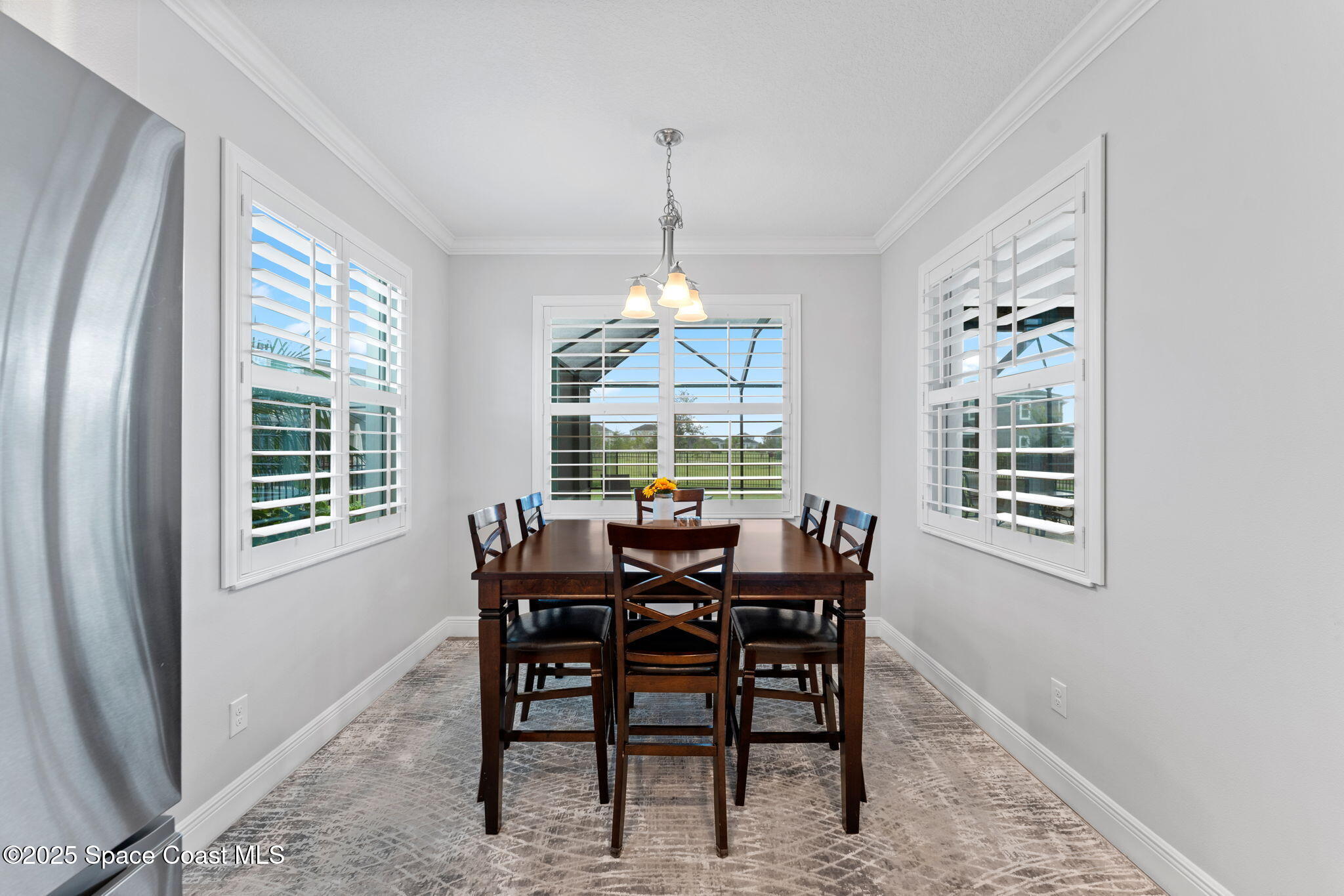 8215 Millbrook Avenue Melbourne, FL 32940 - Photo 21 of 62 a dining room with furniture a chandelier and window