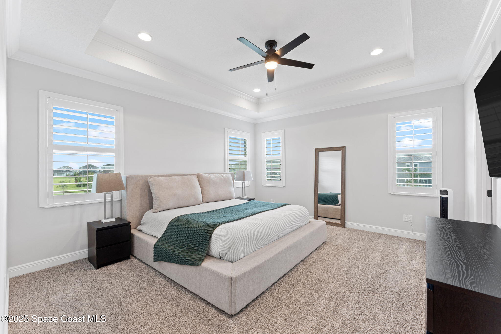 8215 Millbrook Avenue Melbourne, FL 32940 - Photo 25 of 62 a spacious bedroom with a large bed chandelier and a window