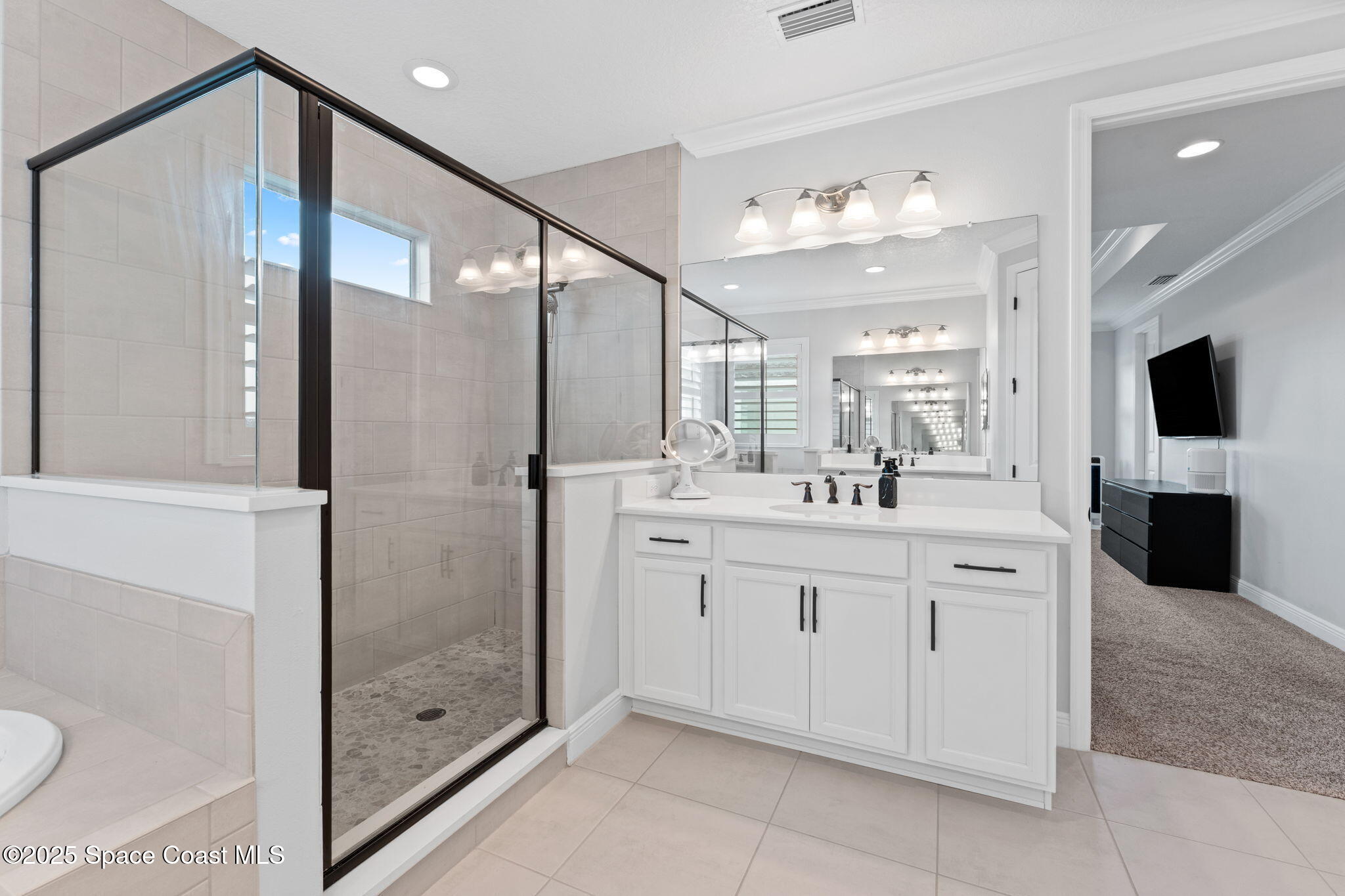 8215 Millbrook Avenue Melbourne, FL 32940 - Photo 29 of 62 a spacious bathroom with a shower sink and mirror