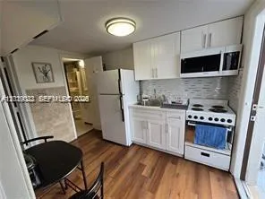 a kitchen with stainless steel appliances a stove a refrigerator a sink a refrigerator white cabinets and wooden floor