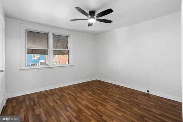 an empty room with wooden floor and a ceiling fan