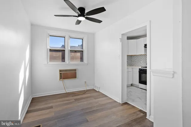 a view of empty room with wooden floor and fan
