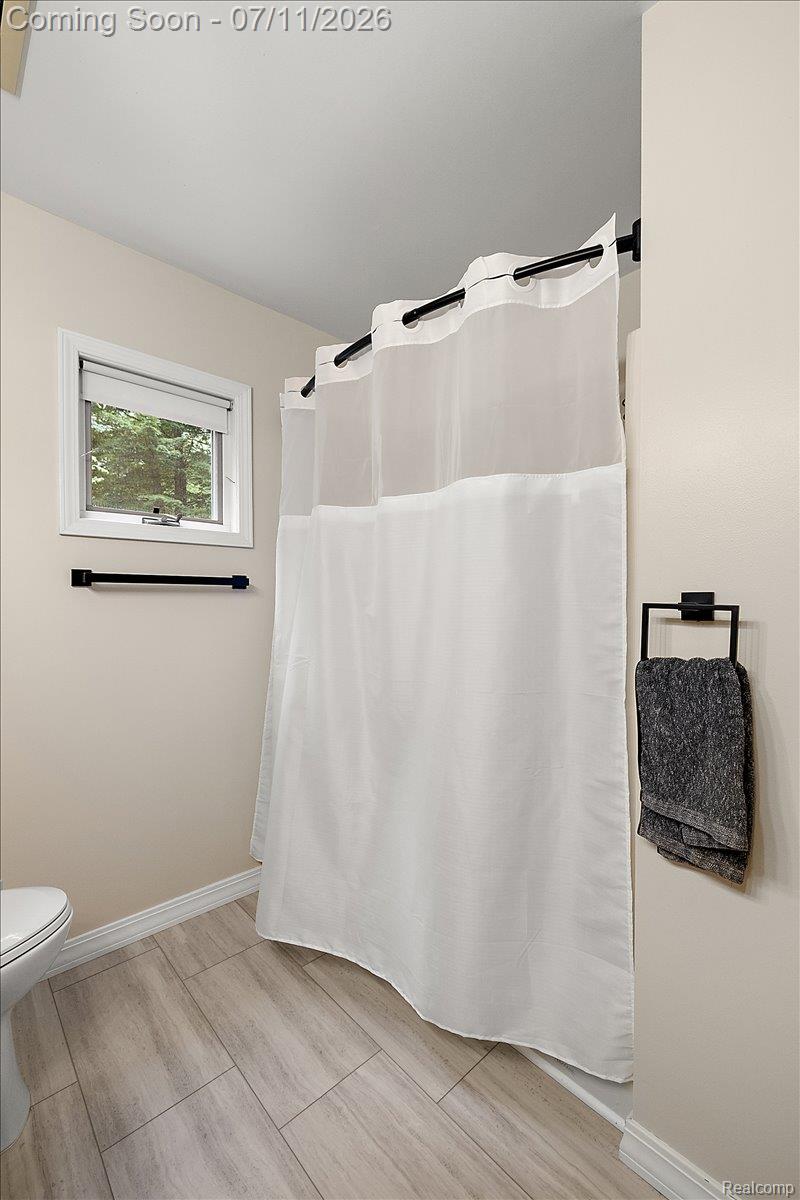 4219 Gardner Road Metamora, MI 48455 - Photo 40 of 87 Bathroom featuring a shower with a white curtain on a black rod, light wood-look tile flooring, and a window with natural light