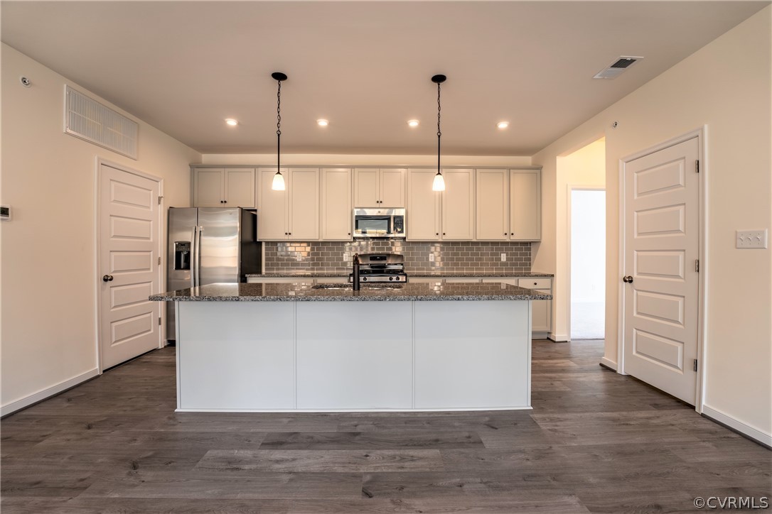 a large kitchen with white cabinets stainless steel appliances and a center island