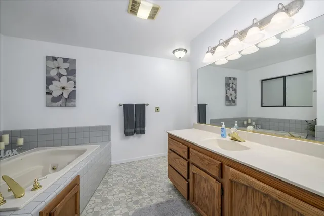 a spacious bathroom with a tub sink and mirror