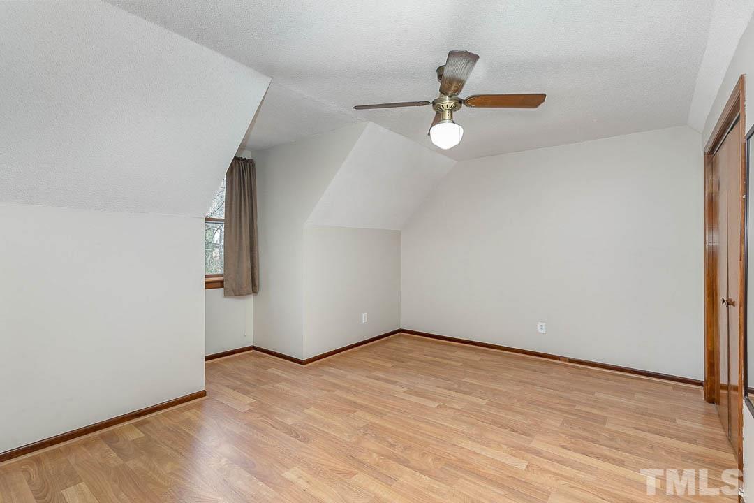 7244 Mine Shaft Road Raleigh, NC 27615 - Photo 14 of 23 an empty room with wooden floor chandelier fan and windows