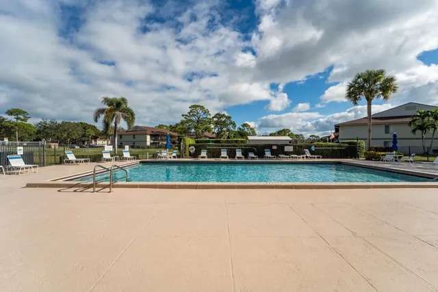 a view of swimming pool with outdoor seating and trees in the background
