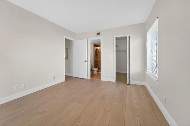 a view of an empty room with wooden floor and closet