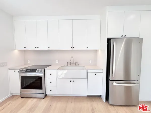 a kitchen with stainless steel appliances white cabinets and a refrigerator