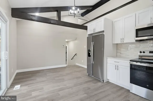 a view of a kitchen with stainless steel appliances granite countertop a refrigerator and a stove top oven