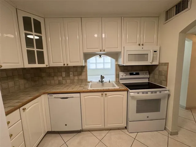 a kitchen with white cabinets a refrigerator and a stove