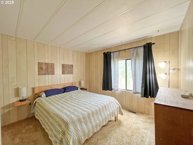 a bedroom with a bed and a dresser next to a window