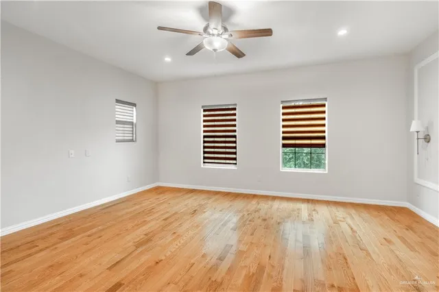 a view of empty room with wooden floor and fan
