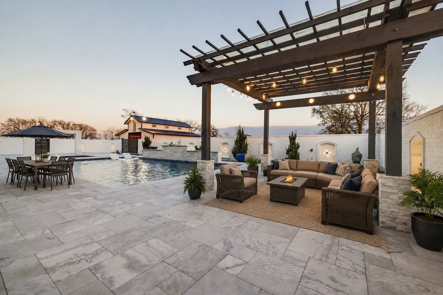 4821 Walters Road Richmond, TX 77469 - Photo 11 of 50 This stunning heated luxury pool creates a true resort-style experience with sleek modern design, expansive lounging areas, and breathtaking sunset views. Featuring elegant marble-style decking, in-water chaise loungers, ambient accent lighting, and a striking stone water feature, the space was thoughtfully designed for both relaxation and entertaining. A covered pergola lounge adds the perfect setting for evening gatherings, while the oversized pool offers a seamless blend of comfort & privacy.