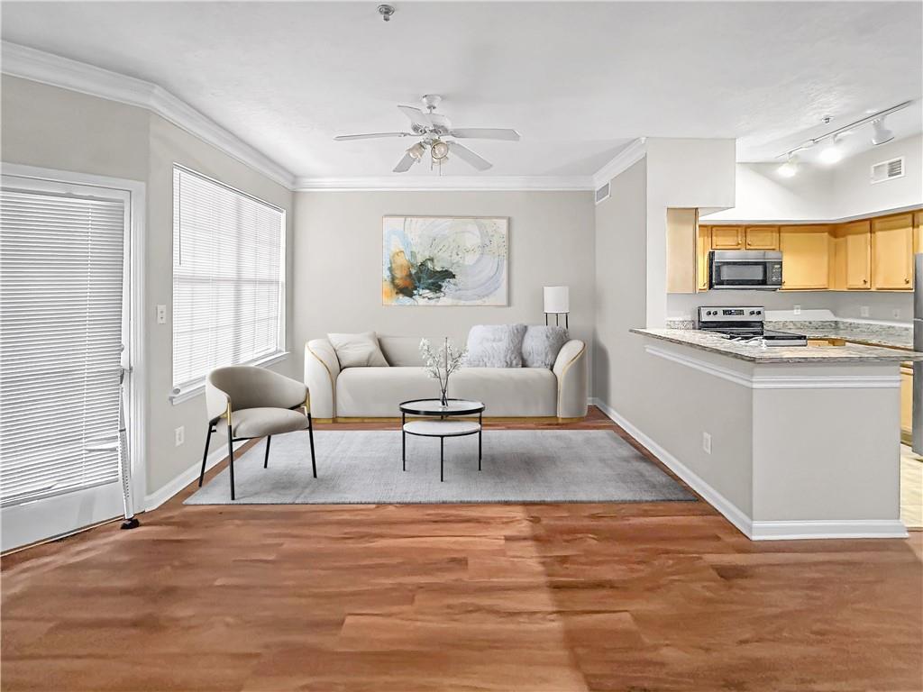 a living room with stainless steel appliances granite countertop furniture and a wooden floor