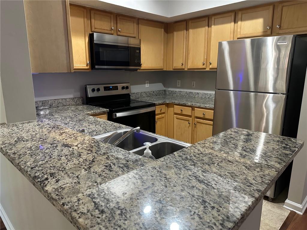 245 Amal Drive Southwest, Unit 2008 Atlanta, GA 30315 - Photo 11 of 23 a kitchen with granite countertop wooden cabinets and a stove