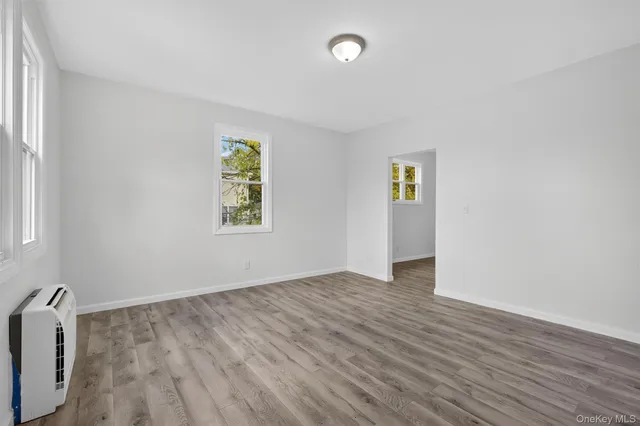 an empty room with wooden floor and window