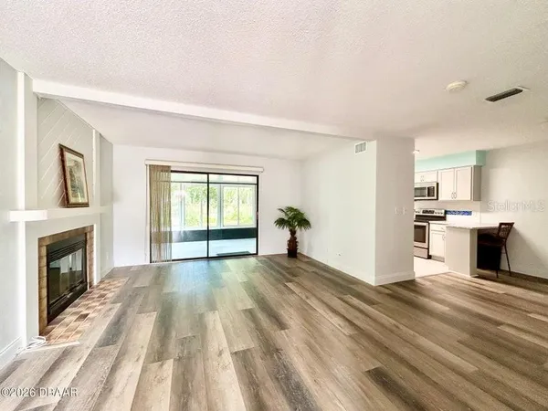 a view of empty room with wooden floor and fireplace