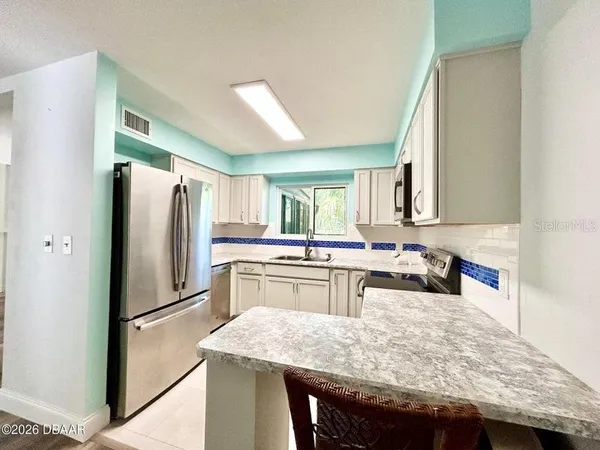 a kitchen with stainless steel appliances granite countertop a refrigerator a sink dishwasher a stove with white cabinets and wooden floor