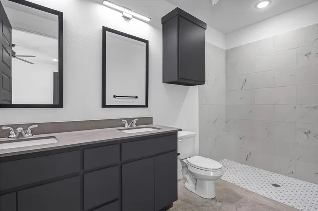 a bathroom with a toilet sink double vanity and mirror