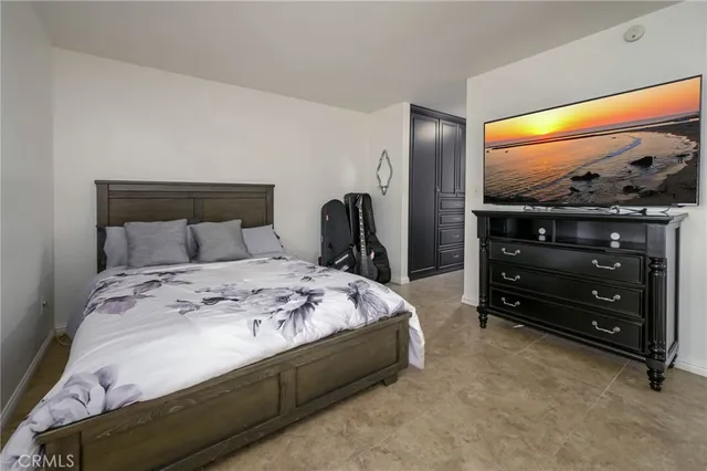 a bedroom with a bed and a flat tv screen on dresser