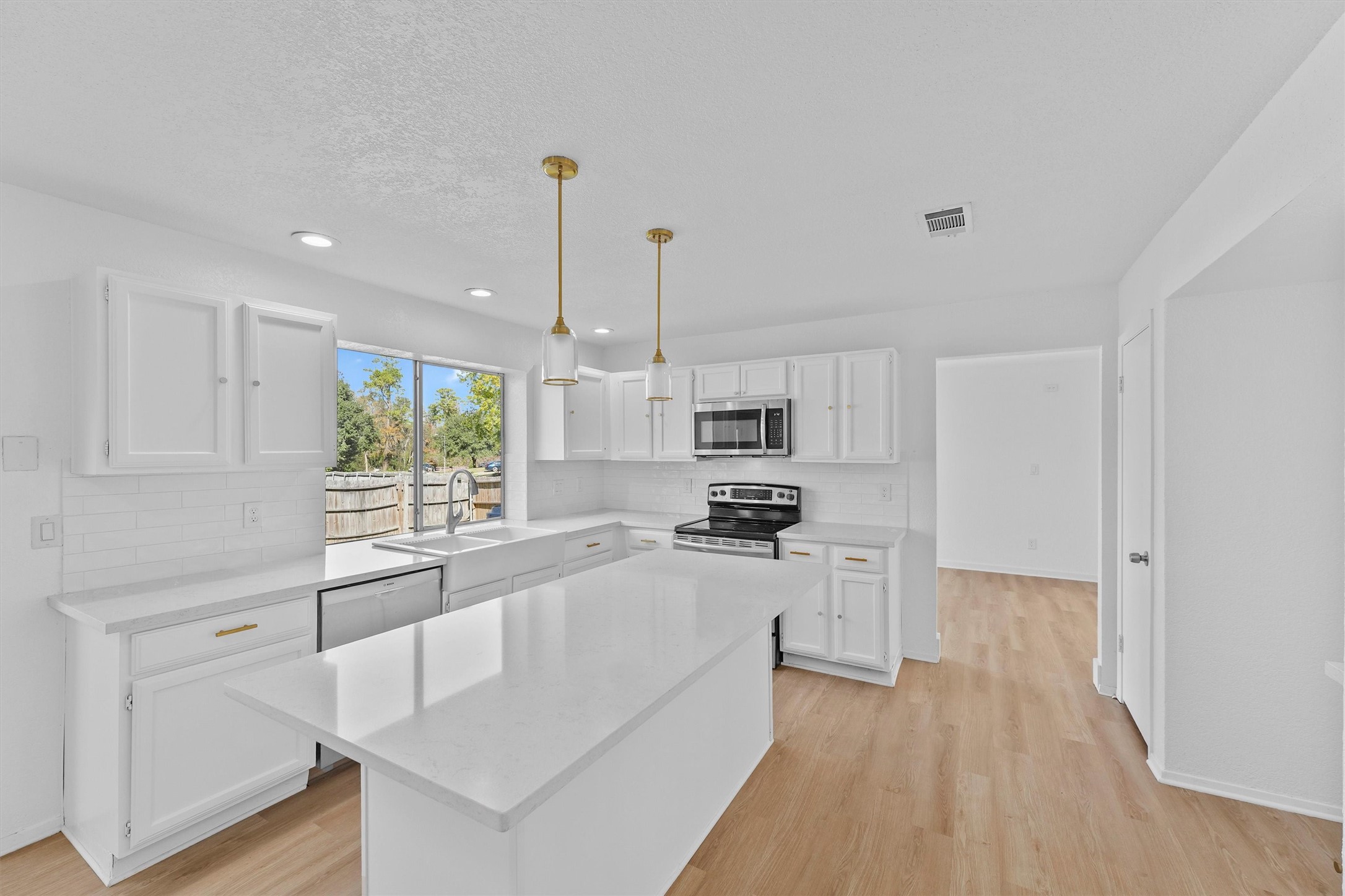 3223 Deer Valley Drive Spring, TX 77373 - Photo 9 of 25 a large kitchen with kitchen island granite countertop a stove a sink a refrigerator and white cabinets with wooden floor