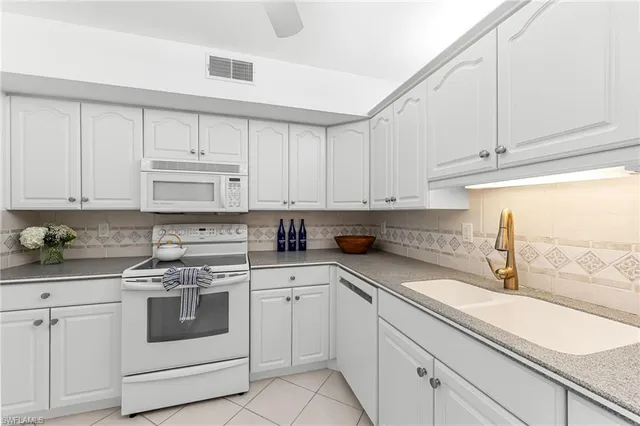 a kitchen with white cabinets and sink