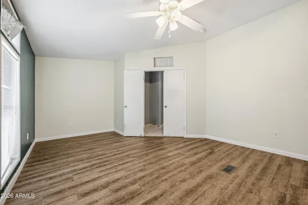 an empty room with wooden floor fan and windows