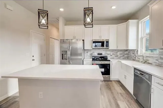 a kitchen with granite countertop a refrigerator stove top oven and sink