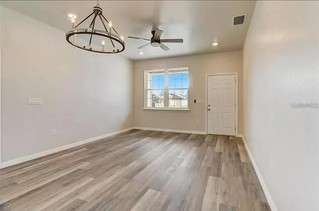 a view of empty room with wooden floor and window