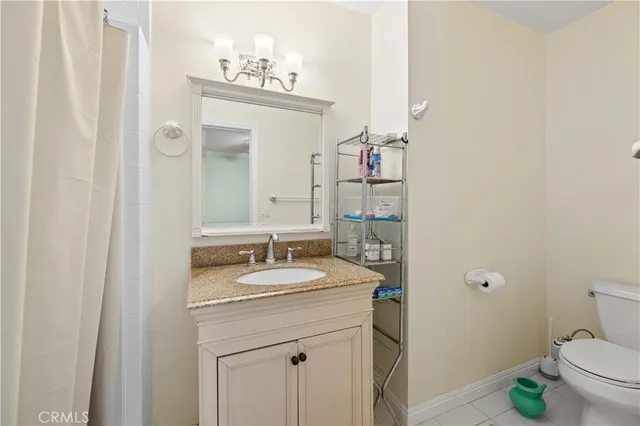 a bathroom with a granite countertop sink a toilet and a mirror
