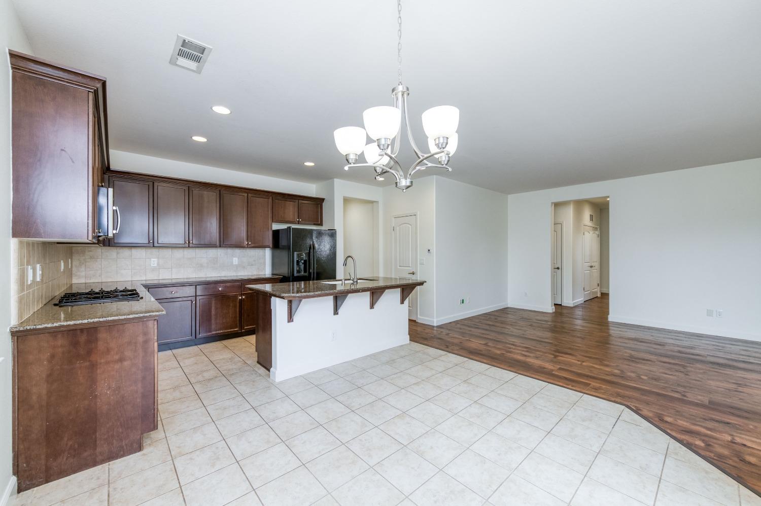1697 North Connery Lane Clovis, CA 93619 - Photo 14 of 56 a kitchen with kitchen island stainless steel appliances granite countertop a sink a stove and a wooden floors