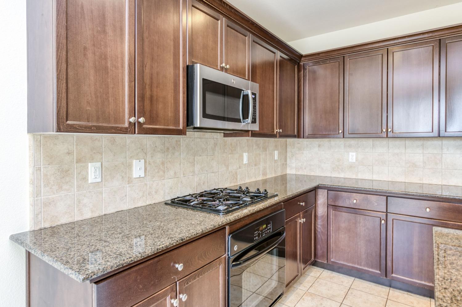 1697 North Connery Lane Clovis, CA 93619 - Photo 15 of 56 a kitchen with granite countertop a stove and a sink
