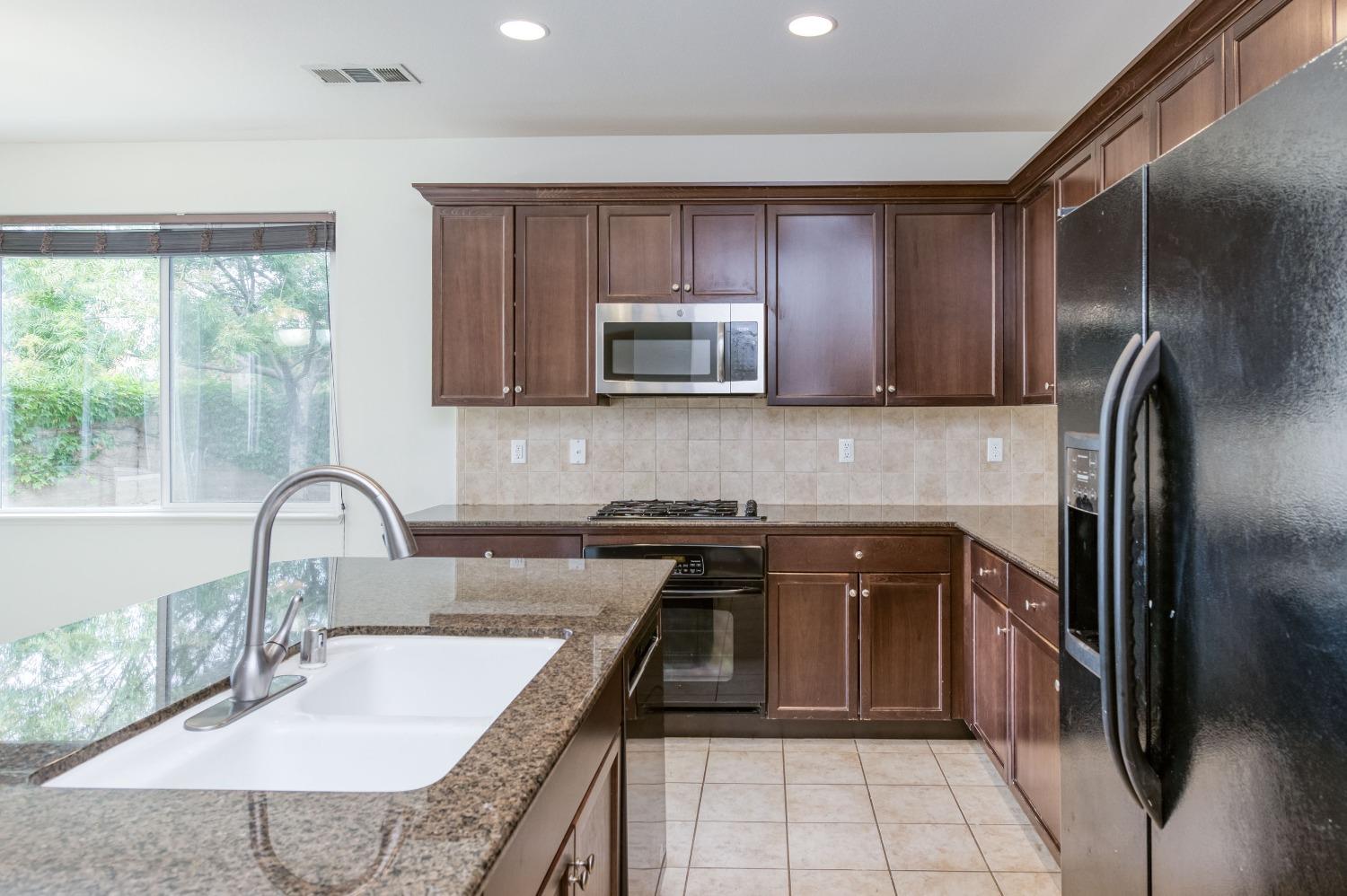 1697 North Connery Lane Clovis, CA 93619 - Photo 17 of 56 a kitchen with granite countertop a refrigerator and a sink