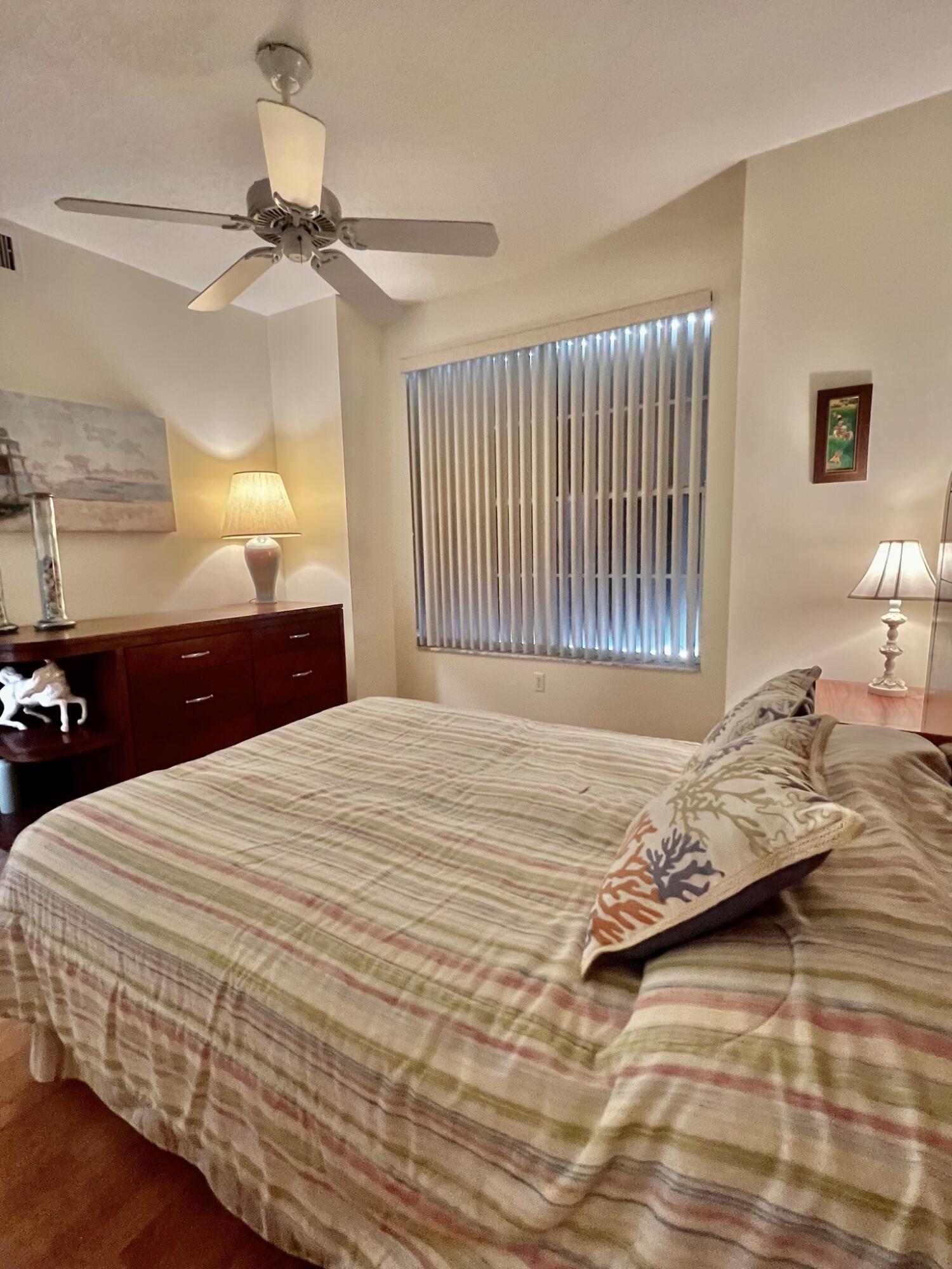 101 Muirfield Court, Unit F Jupiter, FL 33458 - Photo 16 of 20 a bedroom with a bed and a chandelier