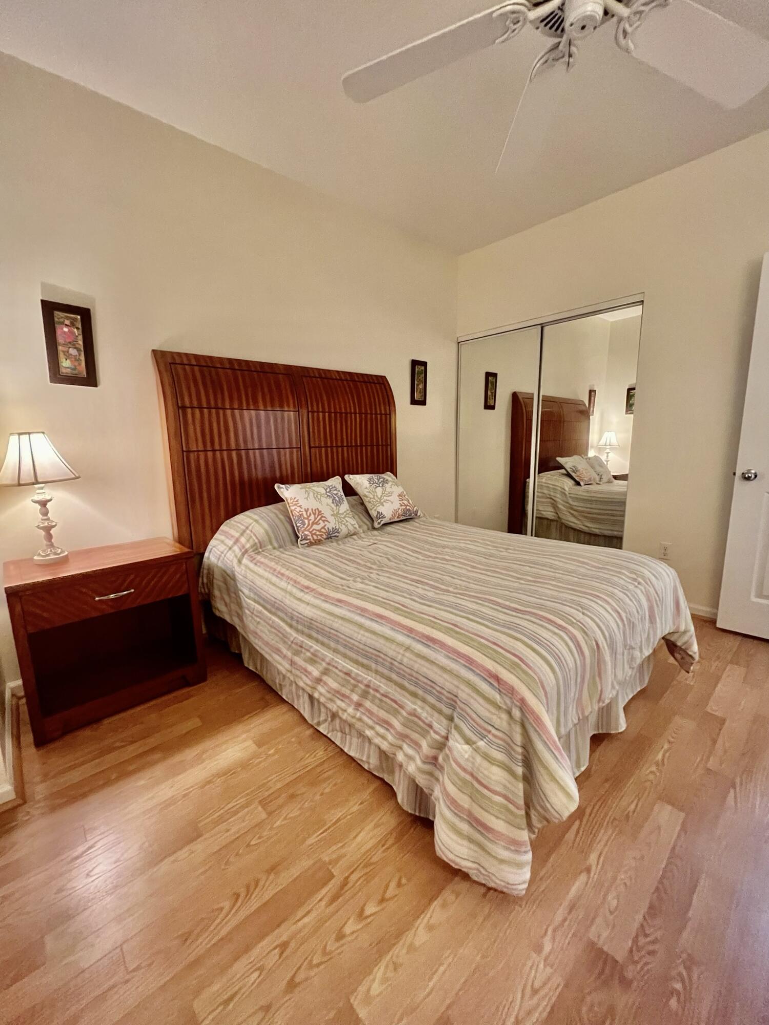 101 Muirfield Court, Unit F Jupiter, FL 33458 - Photo 17 of 20 a bedroom with a bed and a lamp on the dresser