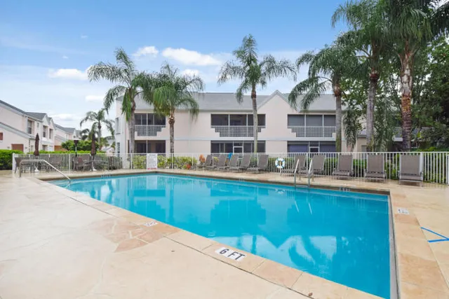 a view of a swimming pool with a lawn chairs under an umbrella
